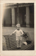 CARTE PHOTO - Bébé Debout Sur Un Banc Public - Chapeau - Nœud Dans Les Cheveux - Carte Postale Ancienne - Photographs