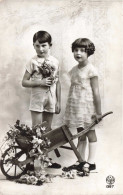 Enfants - Un Frère Et Une Sœur Posant Près D'une Brouette De Fleurs -  Carte Postale Ancienne - Grupo De Niños Y Familias