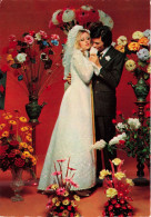 NOCES - L'époux Et La Mariée - Des Mariés Entourés De Fleurs - Murs Rouges - Colorisé - Carte Postale - Marriages