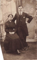 COUPLE - Un Couple Habillé En Noir - Femme Assise Sur Une Chaise - Carte Postale Ancienne - Koppels