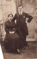 COUPLE - Un Couple Habillé En Noir - Femme Assise Sur Une Chaise - Carte Postale Ancienne - Couples