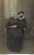 CARTE PHOTO NON IDENTIFIEE REPRESENTANT UNE FEMME ASSISE ET UN GARCON AVEC UN CHAPEAU - A Identifier