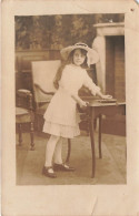 ENFANT - Une Petite Fille Avec Un Chapeau Se Tenant à Côté De La Table - Carte Postale Ancienne - Portretten