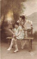 FANTAISIES - Deux Enfants - Une Jeune Fille Tenant Un Bouquet De Fleur Assise - Un Jeune Garçon - Carte Postale Ancienne - Met Mechanische Systemen