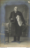 CARTE PHOTO NON IDENTIFIEE REPRESENTANT  UN HOMME EN PARDESSUS CHAPEAU MELON A LA MAIN PAQUETAGE SOUS LE BRAS - A Identifier