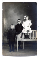 Carte Photo D'une Petite Fille élégante Avec Deux Petit Garcon Posant Dans Un Studio Photo Vers 1920 - Anonyme Personen