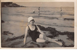 Photographie - N°91006 - Femme En Tenue De Bain Assise Sur Une Plage Entourée D'algues, Au Bord De L'eau - Photographs