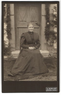 Fotografie W. Breiner, Gronau /Hann., Ältere Dame Im Langen, Taillierten Kleid Vor Ihrer Haustür Sitzend  - Anonymous Persons
