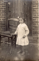 Carte Photo D'une Petite Fille élégante Posant Devant La Porte De Sa Maison - Personnes Anonymes