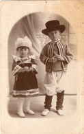 Carte Photo D'une Petite Fille Et Un Petit Garcon En Tenue Régional Posant Dans Un Studio Photo En 1929 - Anonymous Persons