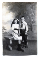 Carte Photo D'une Jeune Fille élégante Avec Un Jeune Garcon Posant Dans Un Studio Photo Vers 1920 - Personnes Anonymes