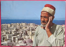 Israël - Acre - The Moazin Calls For Prayer - In The Background Ancient City Of Acre - Israel