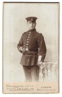 Fotografie Samson & Co., Lübeck, Soldat In Uniform Mit Hand Auf Tisch  - Personas Anónimos