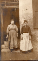 Carte Photo De Deux Femmes En Tenue De Travail Posant Devant La Porte De Leurs Maison En 1911 - Personnes Anonymes