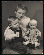 Fotografie Mädchen Hat Puppe Und Kleinkind Auf Dem Schoss Sitzend  - Other & Unclassified