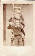 Carte Photo D'une Jeune Fille Avec Deux Jeune Garcons Posant Sur Une Echelle Contre Leurs Maison En 1904 - Anonyme Personen