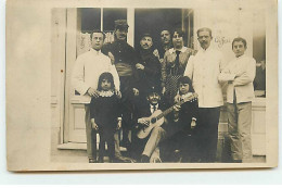 Carte Photo - Groupe De Personnes Devant Un Salon De Coiffure, Autour D'un Homme Avec Une Guitare - Tiendas