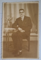 PH Originale - Homme élégant En Costume Et Cravate Posant Assis à Côté D'une Table Avec Des Fleurs - Personnes Anonymes