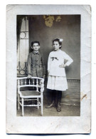 Carte Photo D'une Jeune Fille élégante Avec Un Jeune Garcon Posant Dans Un Studio Photo Vers 1920 - Personnes Anonymes