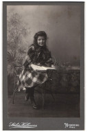 Fotografie Jacob Hellmann, Homburg /Pf., Lächelndes Mädchen In Festlichem Karierten Kleid Mit Einem Bildband  - Anonyme Personen