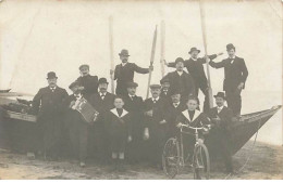 Carte Photo à Localiser - Hommes Devant Une Barque, Un Homme Jouant D'un Accordéon, Et Un Jeune Homme Tenant Un Vélo - To Identify