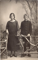 Carte Photo D'une Jeune Fille élégante Avec Un Jeune Garcon Posant Dans Un Studio Photo - Anonymous Persons