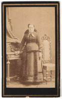 Fotografie J. F. Klinger, Braunau, Stadtgraben 318, Portrait ältere Frau Im Kleid Mit Schleife Steht Im Atelier  - Anonyme Personen