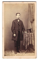 Fotografie W. Filser, Kaufbeuren, Junger Mann Im Anzug Mit Zylinder Auf Dem Tisch  - Anonyme Personen