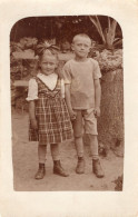 Carte Photo D'une Jeune Fille élégante Avec Un Jeune Garcon Posant Dans La Cour De Leurs Maison Vers 1915 - Anonymous Persons