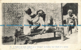 R648715 A Barber At Work Seated On A Charpai Or Indian Bed Which Also Serves. Se - World