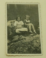 Two Young Girls Are Sitting On A Rock - Anonymous Persons