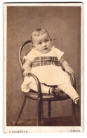 Fotografie H. Schröder, Lübeck, Beckergrube 150, Kleiner Junge Im Kleid Sitzt Auf Einem Stuhl  - Anonyme Personen