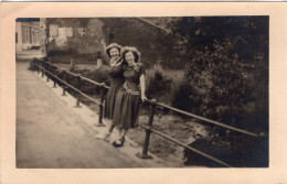 Carte Photo De Deux Femmes élégante Posant Sur Un Pont Sur Une Rivière Dans Un Village - Personas Anónimos