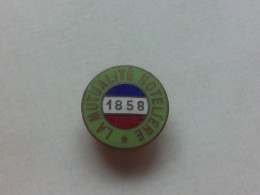 (Organisation - Assurances.......) - Petit Insigne Fraisse Demey  (type Sabot)   " LA MUTUALITE HOTELIERE - 1858   " - Andere & Zonder Classificatie